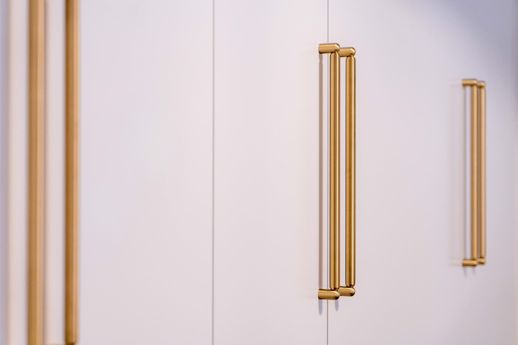 Custom built-in wardrobe with brass handles by A&E Joinery