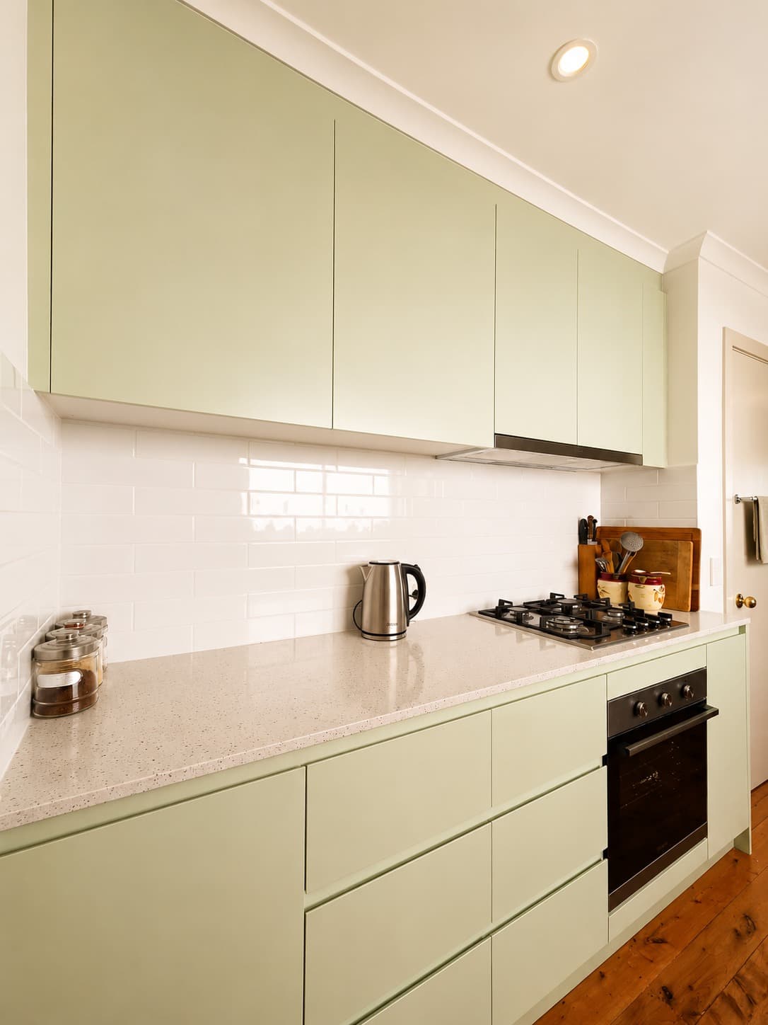 Sage green kitchen cooktop run with handle-less drawer fronts