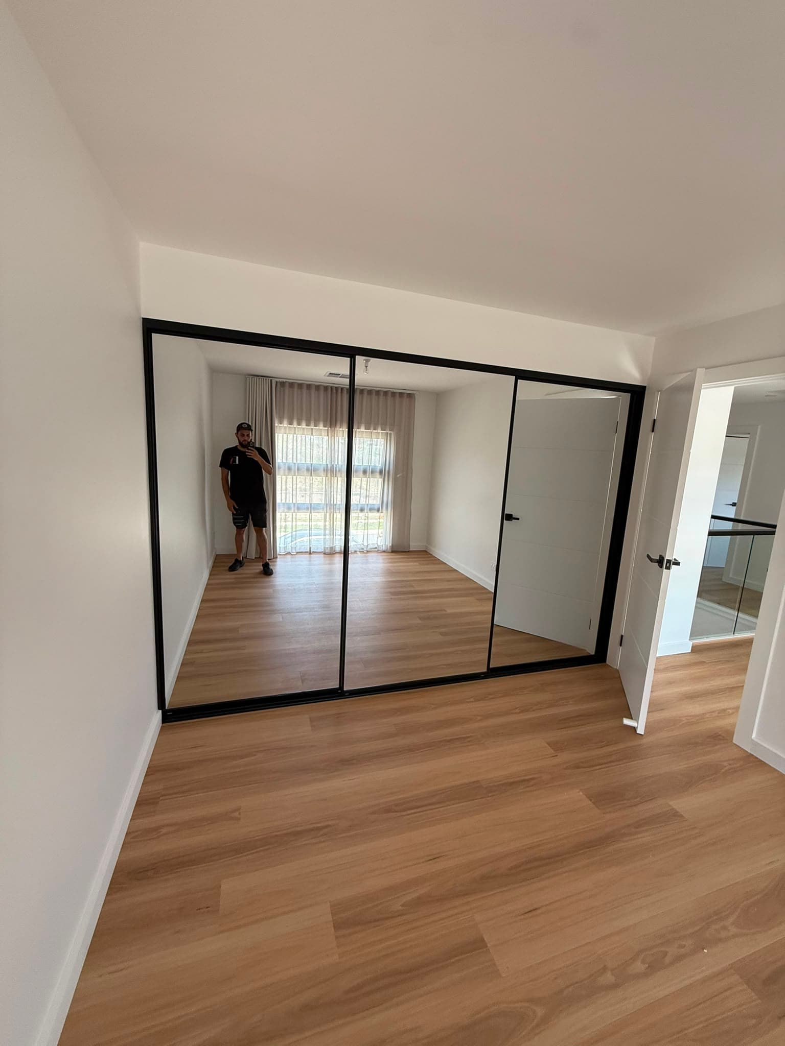 Black-framed mirrored sliding wardrobe doors by A&E Joinery